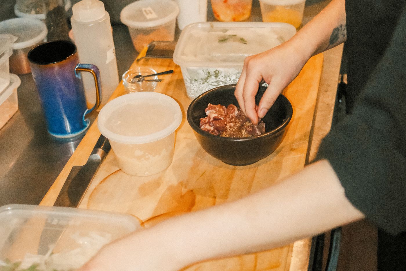 A cook seasoning at a prep station in a restaurant kitchen, the labor hours side of the sales per labor hour formula